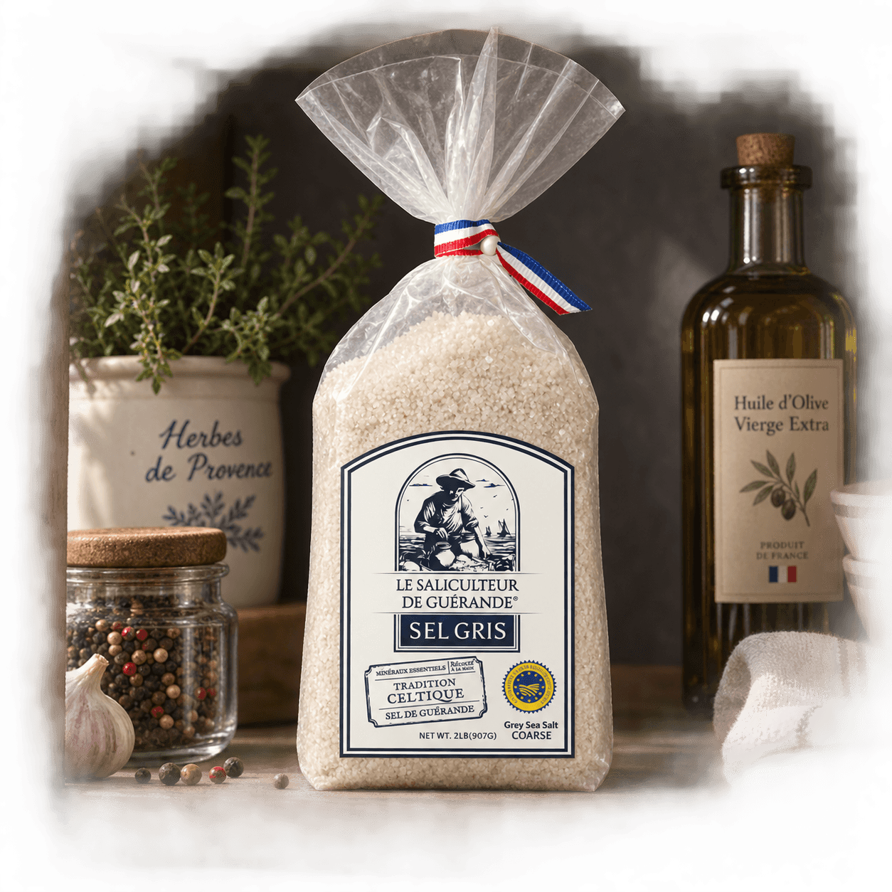 Le Saliculteur de Guérande Celtic Salt Coarse, 907g bag on a kitchen shelf with herbs, olive oil and peppercorns